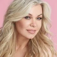 “Blonde woman smiling against a pink background”