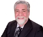 Smiling older man with gray hair and beard in a suit