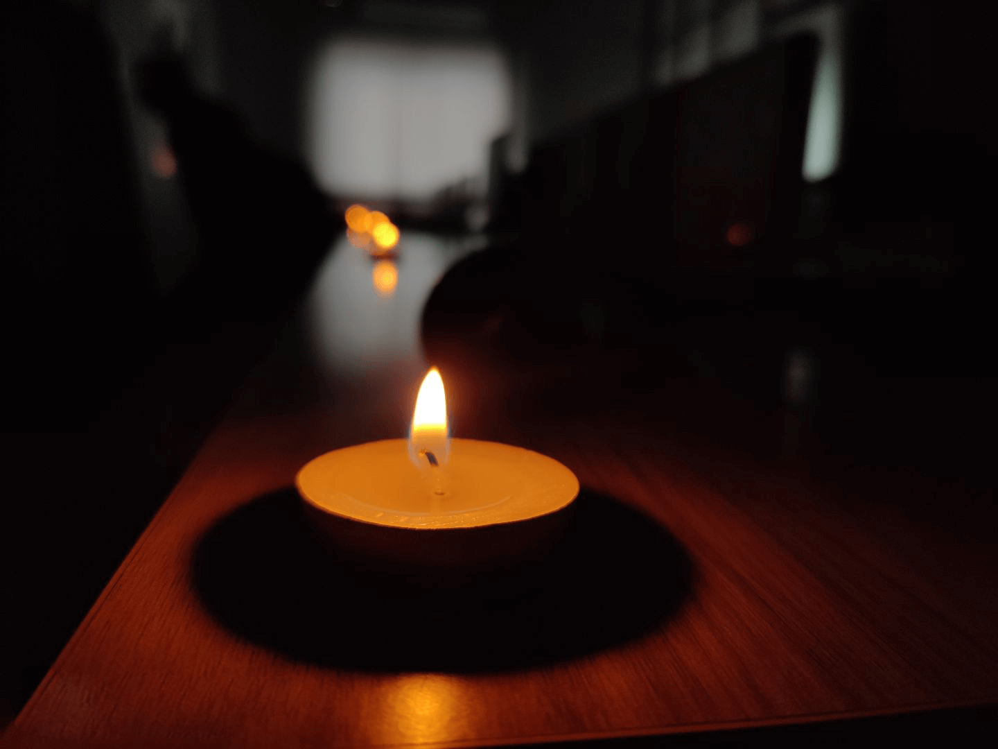 A lit candle on a table in a dark office, creating a warm, calm glow.